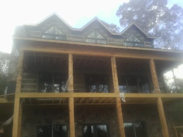 Dormers and porch framing on a large log home under construction — Roof Coating work by our crew in Chapin