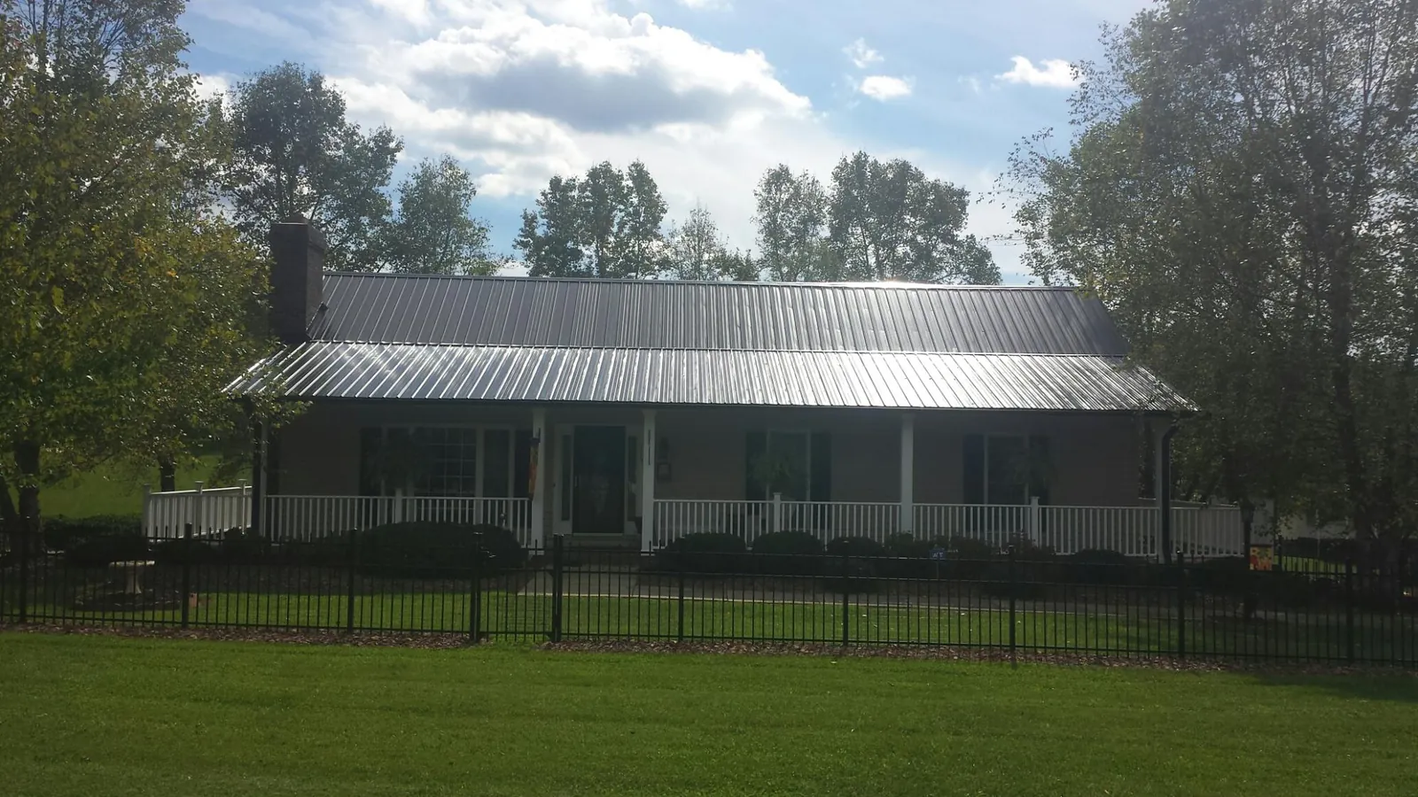 Gray metal roof on a brick ranch with a full width front porch — Gutter Guard Installation work by our crew in Chapin
